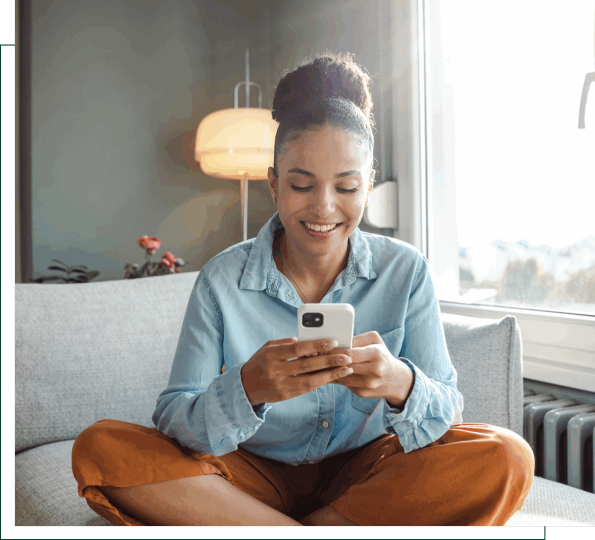 Woman smiling while using a smartphone indoors.